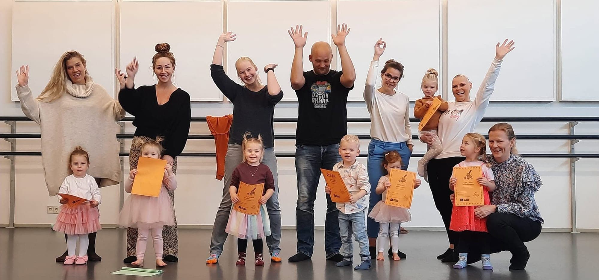 Dreumesen en hun ouders juichen samen in de balletzaal, een kind houdt trots een diploma omhoog