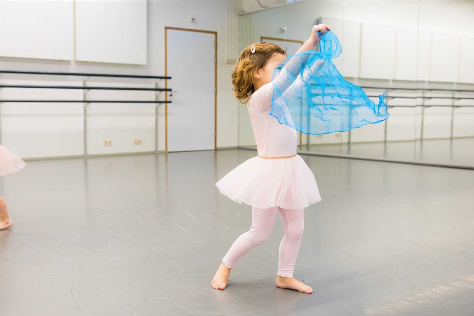 Peuter danst met een blauwe sjaal tijdens de les